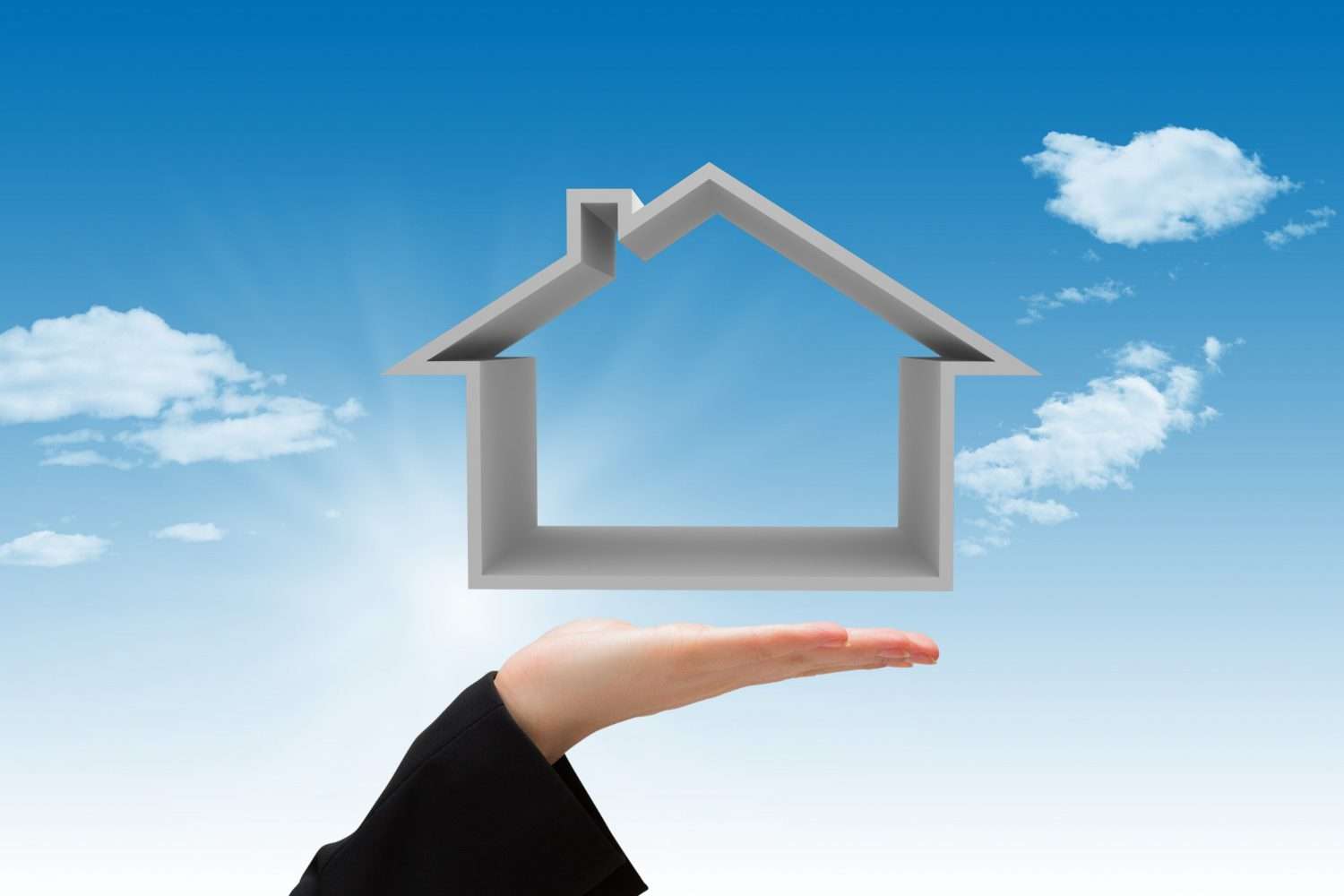 fs A hand holds a house-shaped outline against a blue sky with clouds.